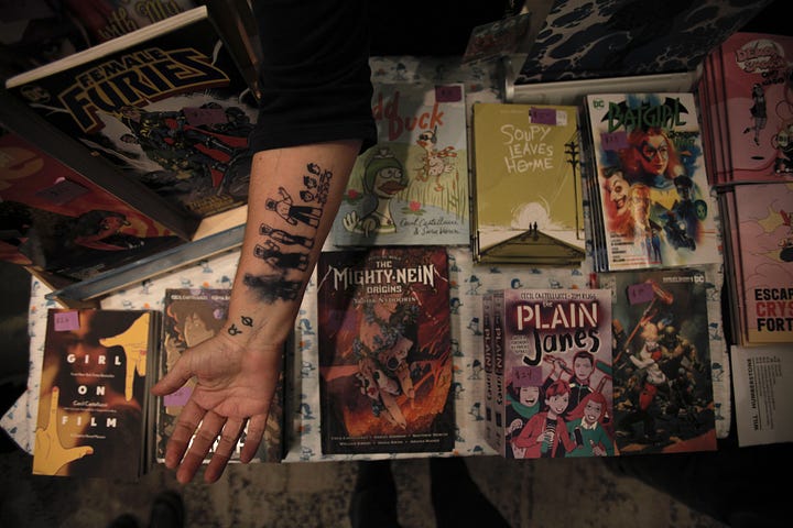 Cecil's arm sporting a tattoo of a little person on top of a stack of books. Next to an image of a flyer for the Oper'Actuel in text.