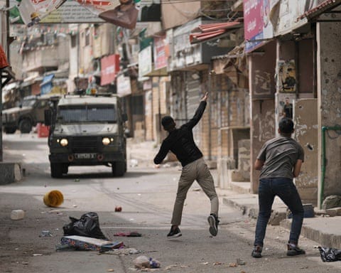 Palestinians throwing stones at Israeli forces during a military raid in the West Bank.
