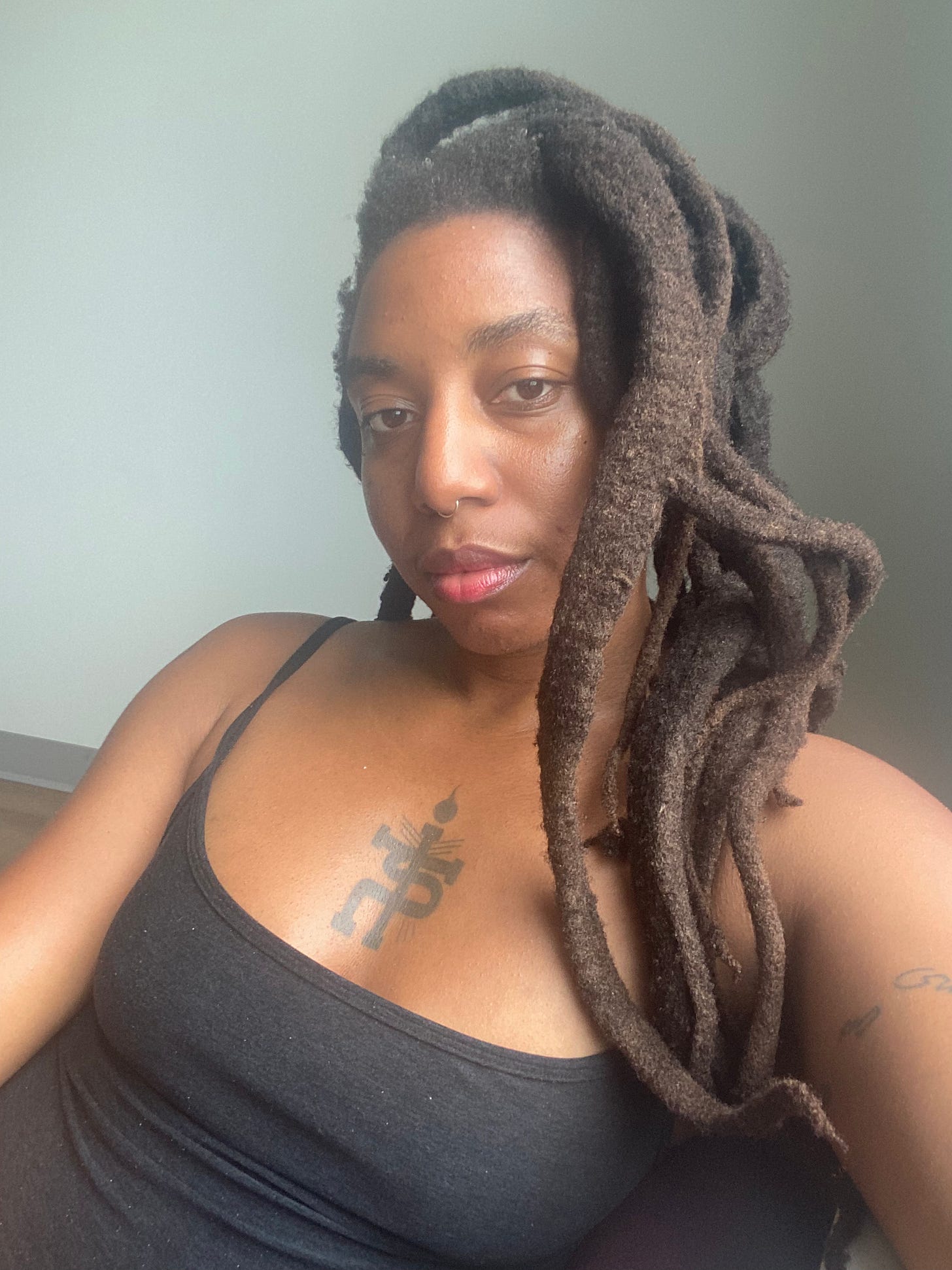 n3vlynnn beautiful black woman with locs gazing into the camera.