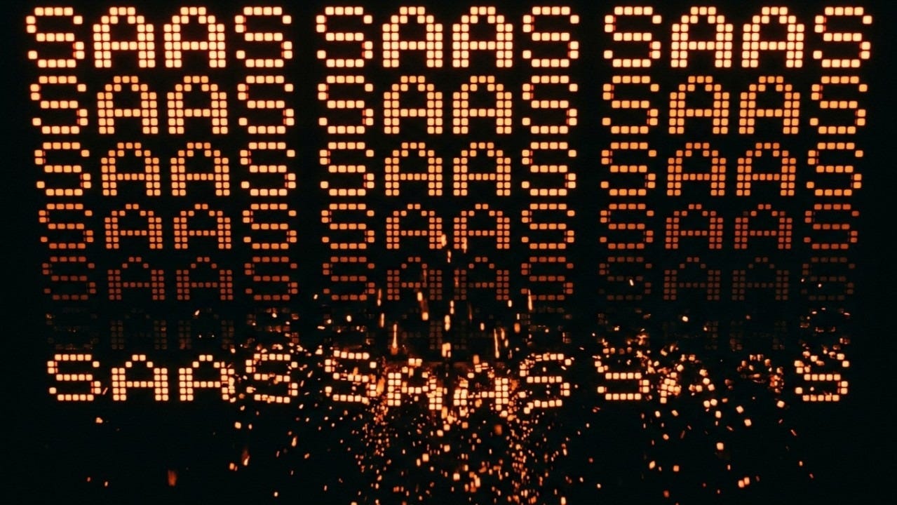 Glowing “SAAS” text repeating in rows, breaking apart into sparks at the bottom—symbolizing the fragmentation and disruption of SaaS models. Glowing “SAAS” text repeating in rows, breaking apart into sparks at the bottom—symbolizing the fragmentation and disruption of SaaS models.