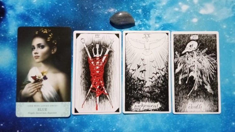 Elle Qui and Wild Unknown Tarot cards and gray stone with purple flash on starry blue background