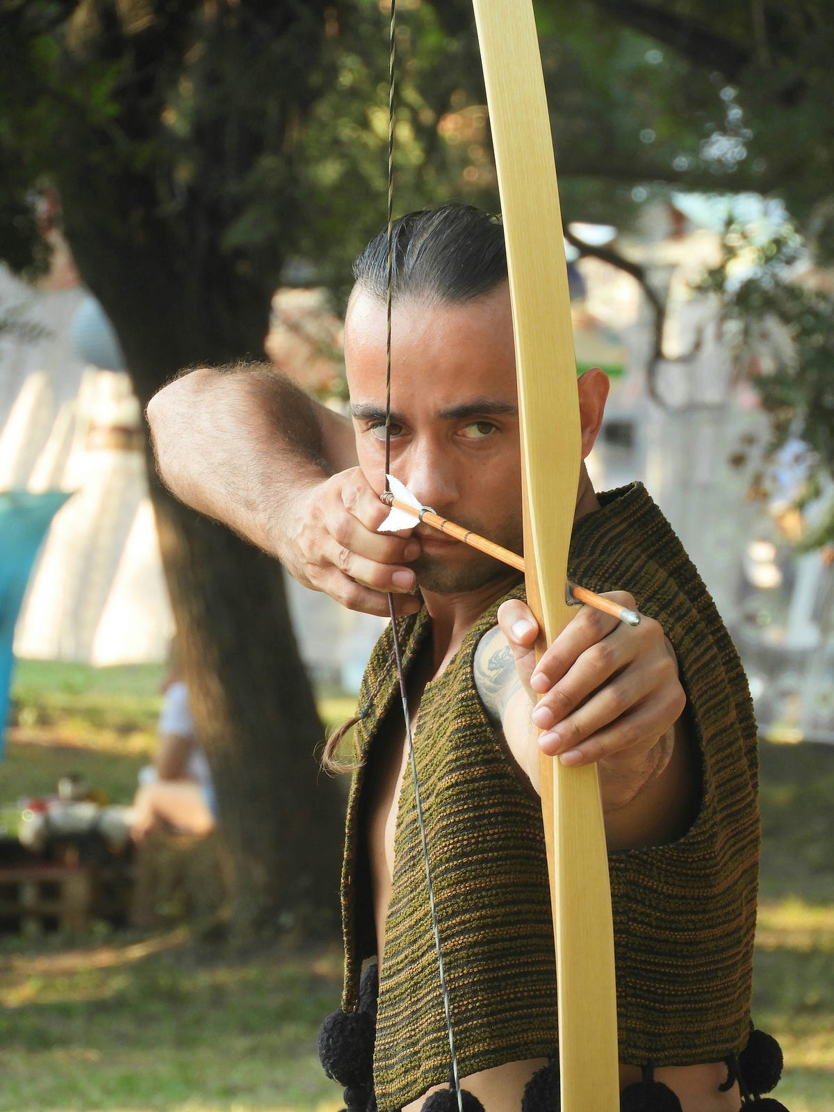 An archer with drawn bow and arrow, aiming down to the right.