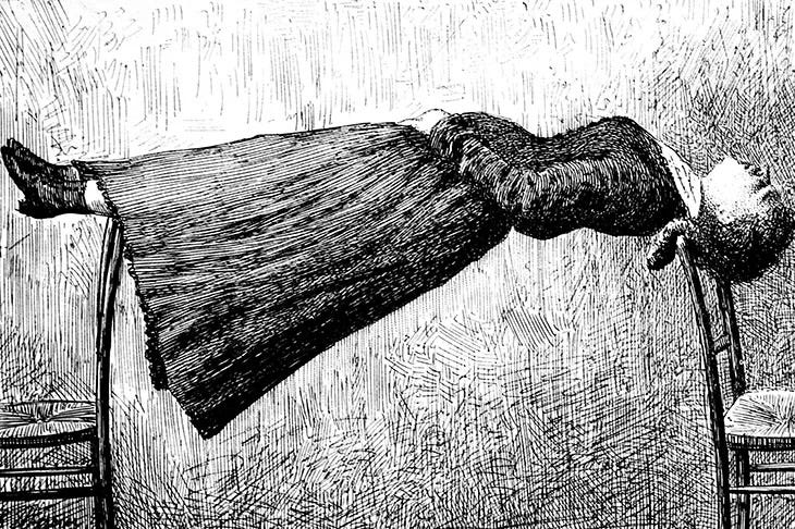 A black and white etching of a woman in Victorian dress and boots hovering stiffly between two chairs