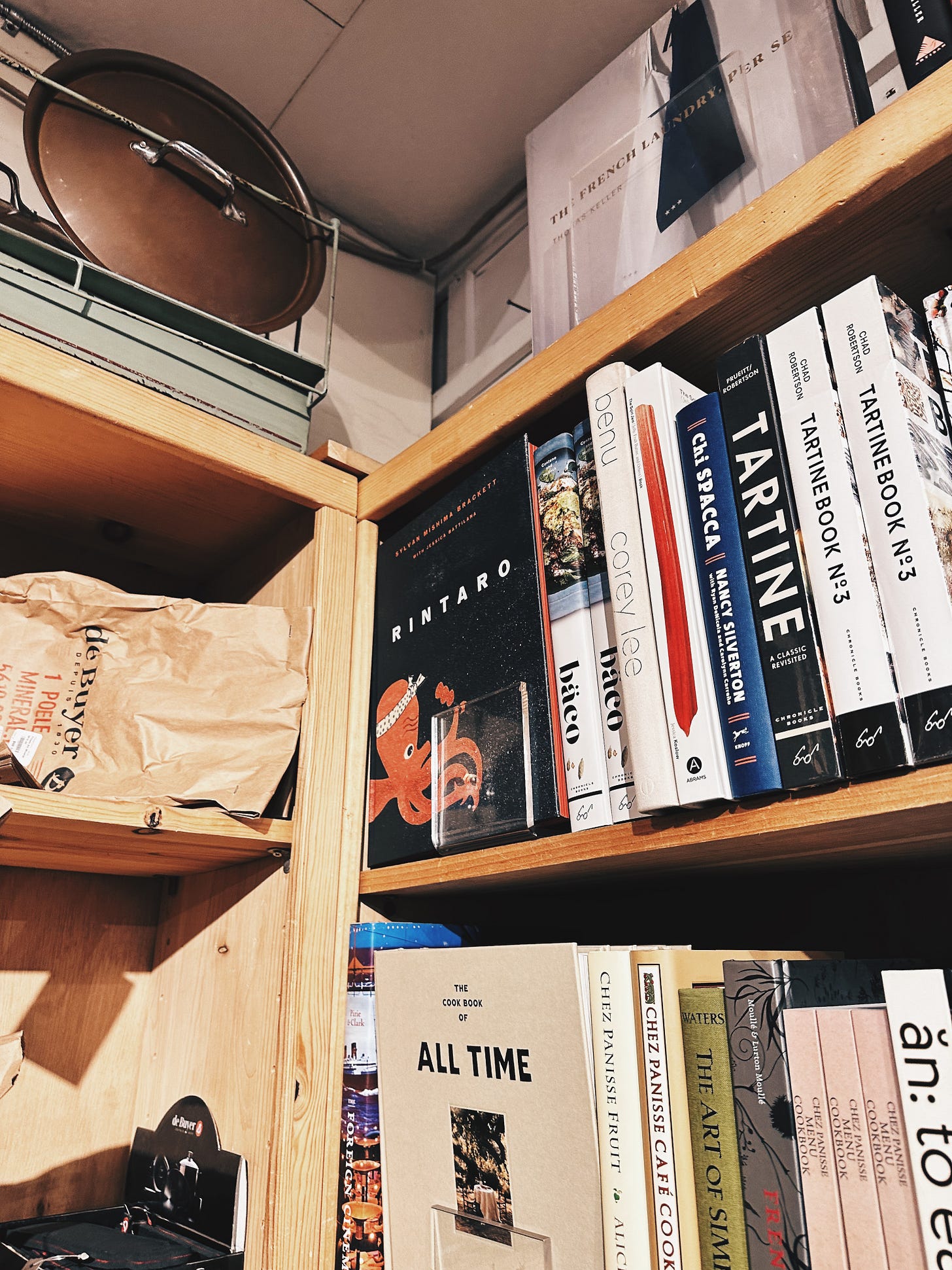 Curated cookbook selection at Peppercorn Boulder including culinary reference books and kitchen design titles on wooden shelves Curated cookbook selection at Peppercorn Boulder including culinary reference books and kitchen design titles on wooden shelves