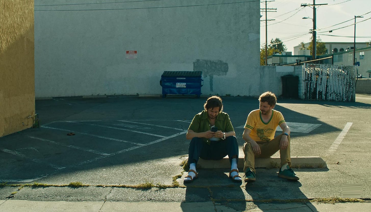 Two men sit disconsolately in an empty parking lot