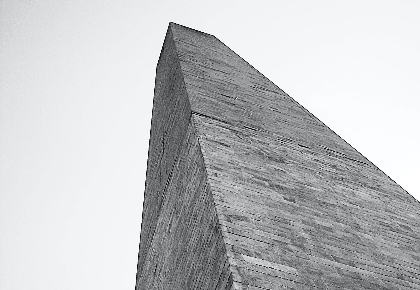 A black and white photo of the Washington Monument, in forced perspective.