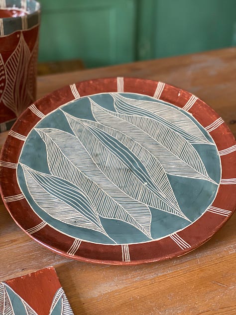 ceramic pieces decorated with a nature abstract design using slips and sgraffito: two platters, two flat panels and a vase