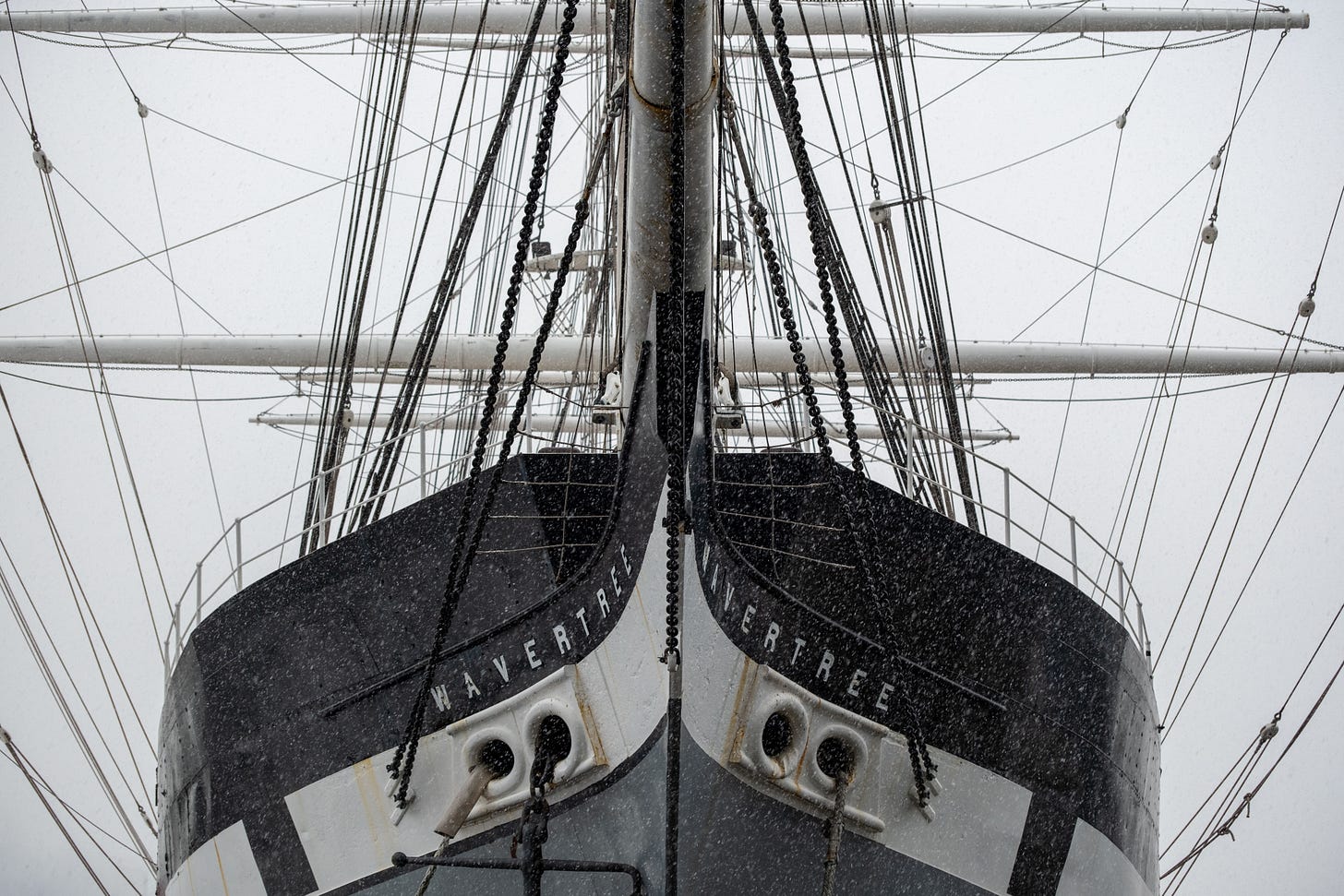 The bow of the tall ship Wavertree in falling snow, a privateer-era hull held to a modern mooring. The bow of the tall ship Wavertree in falling snow, a privateer-era hull held to a modern mooring.