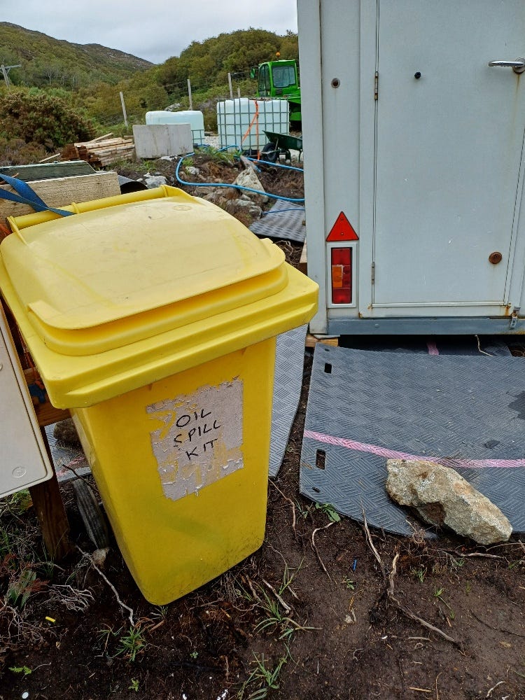 A yellow bin with 'Oil Spill Kit' written on it, beside the welfare wagon, with matting in front of the door.