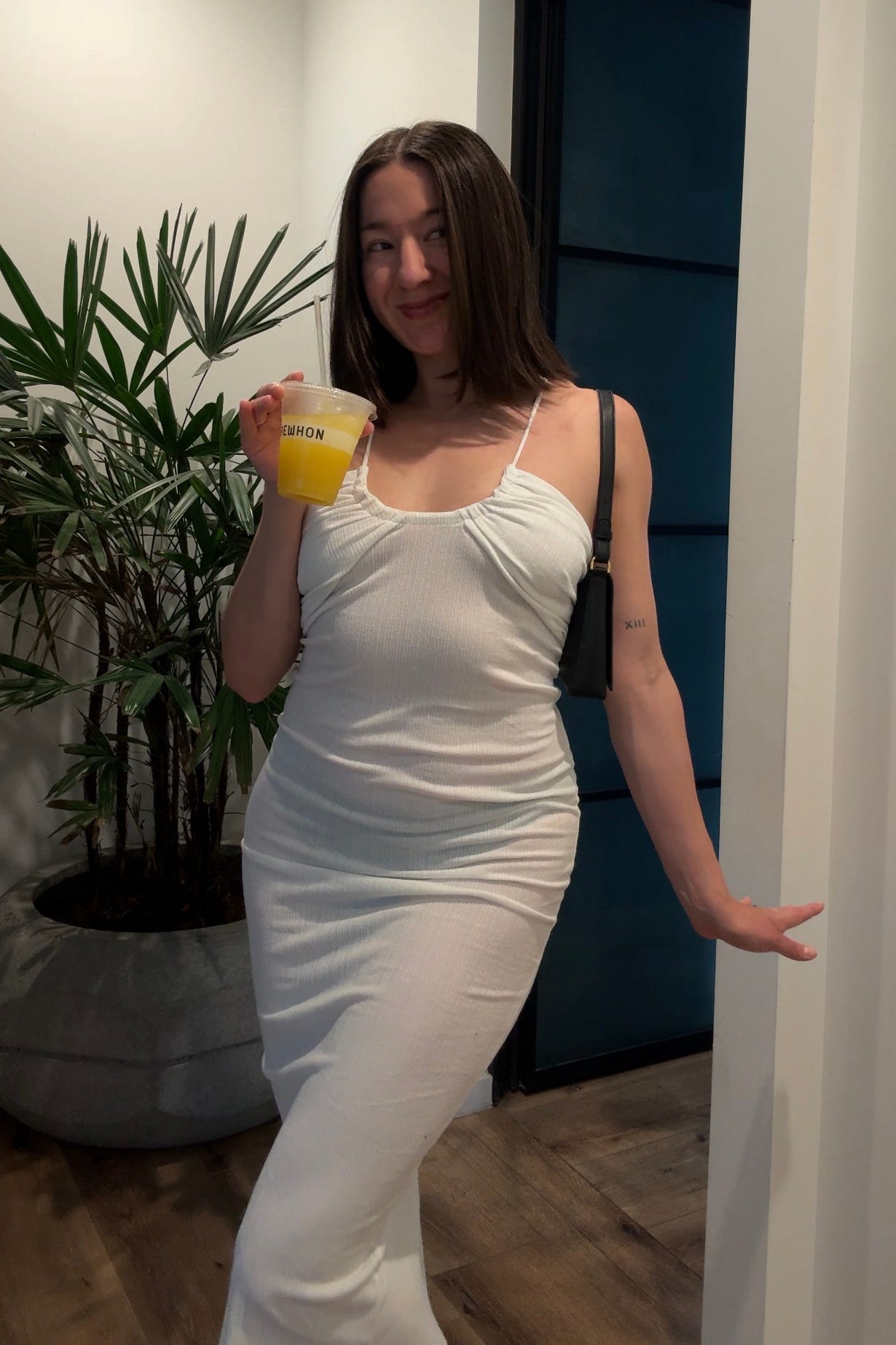 Author Melina Maria Morry wears a white Musier Paris dress with an Aupen bag and Erewhon smoothie.