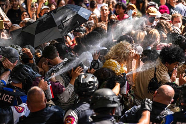 Police pepper spray protesters that are blocking police vehicles from leaving the University of Texas at Austin on Monday, April 29, 2024. Protesters created an encampment on the UT Tower south lawn meant to call attention to the war in Gaza and to condemn the University of Texas at Austin’s relationship with defense companies. Protesters were given notices to vacate and were then removed by Austin Police, University police, and Texas State Troopers.