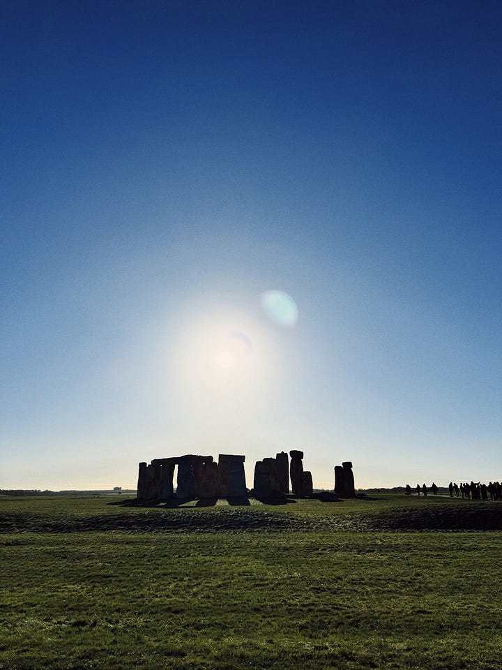 four photos, featuring stonehenge, a bowl full of colourful pasta, a sugar-coated pastry and coffee, and a hand holding cards for a board game.
