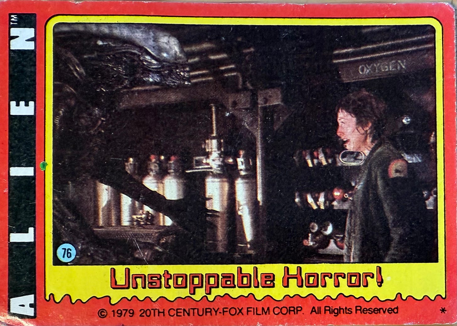 A Topps trading card for the “Alien” movie. The title “Alien” runs vertically as white text on a black ribbon, along the left-hand side. The background of the card is red. In a yellow frame there is a photo of a scene from the movie in which the alien menaces the terrified character Lambert, played by actress Veronica Cartwright. The background is a rack of tanks labeled “oxygen.” Below the photo, in the yellow frame, the caption “Unstoppable Horror” is rendered in red letters in an old-school OCR font that probably seemed futuristic at the time. The card is labeled as #76 in a series. At the bottom, in the red border, is the line (c) 1979 20th Century Fox Film Corp. All Rights Reserved, in small, black text.