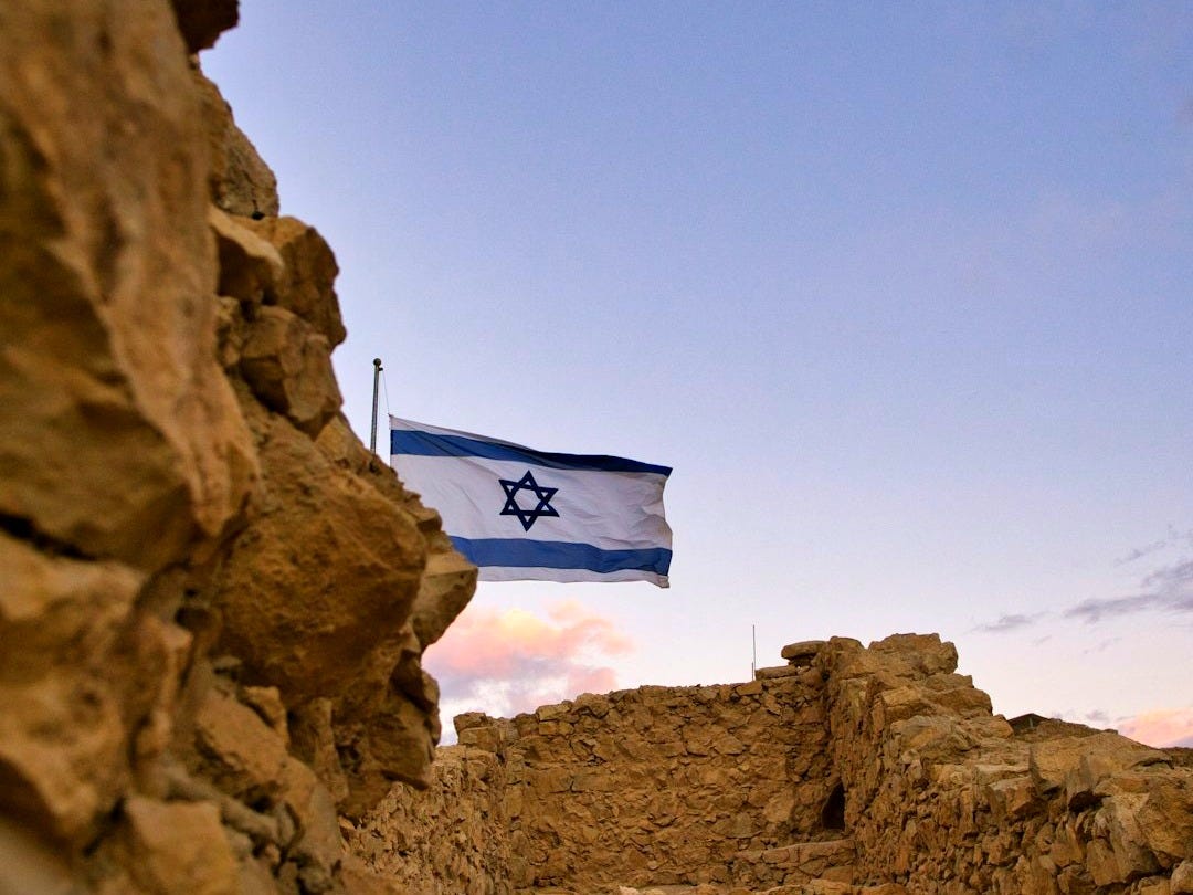 an israeli flag flying over a rocky area
