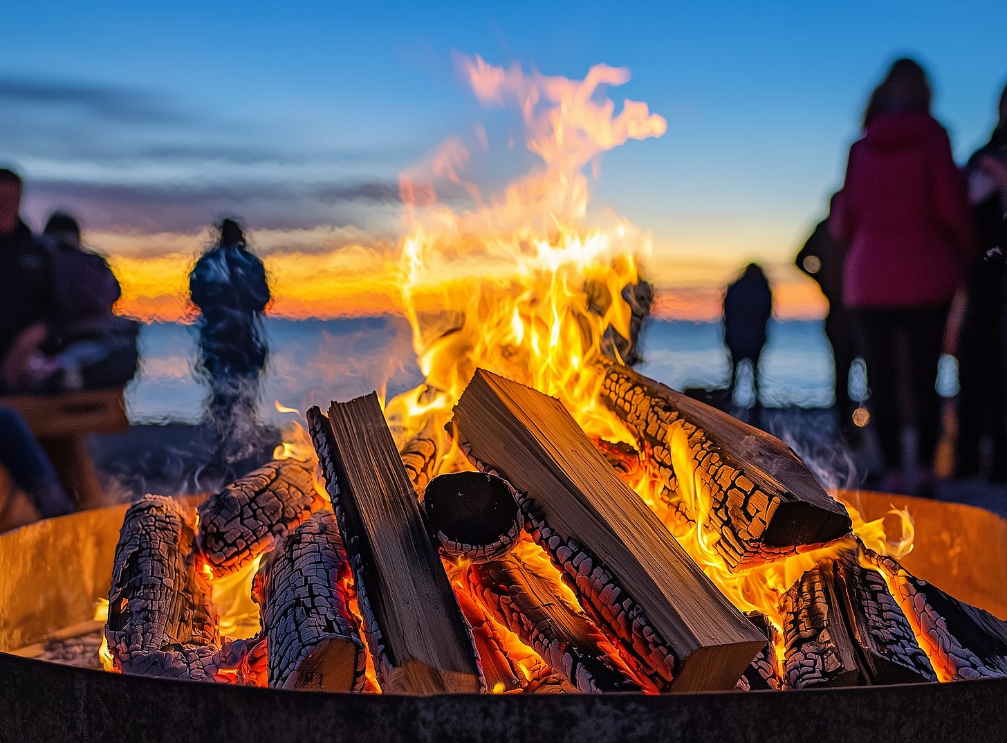 A fire on the beach with people gathered around A fire on the beach with people gathered around