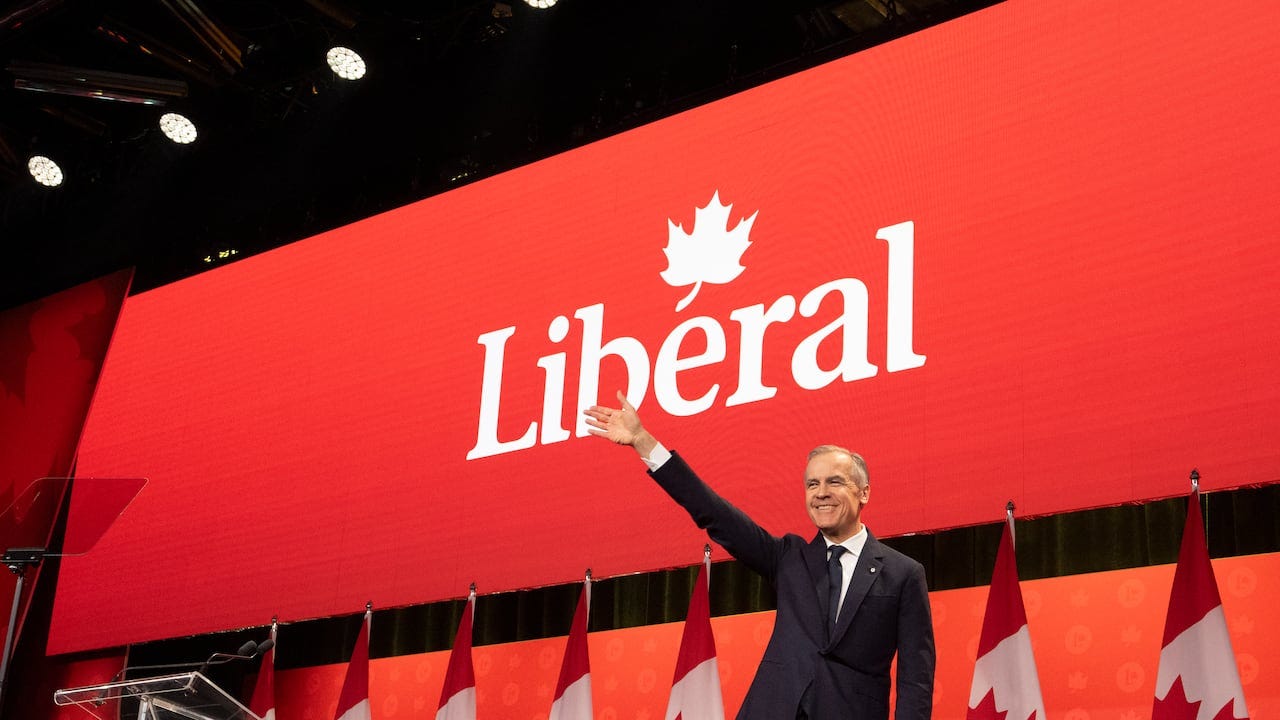 Prime Minister Mark Carney waves against a red background 