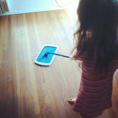 A small girl seen from above is mopping a bare wood floor A small girl seen from above is mopping a bare wood floor
