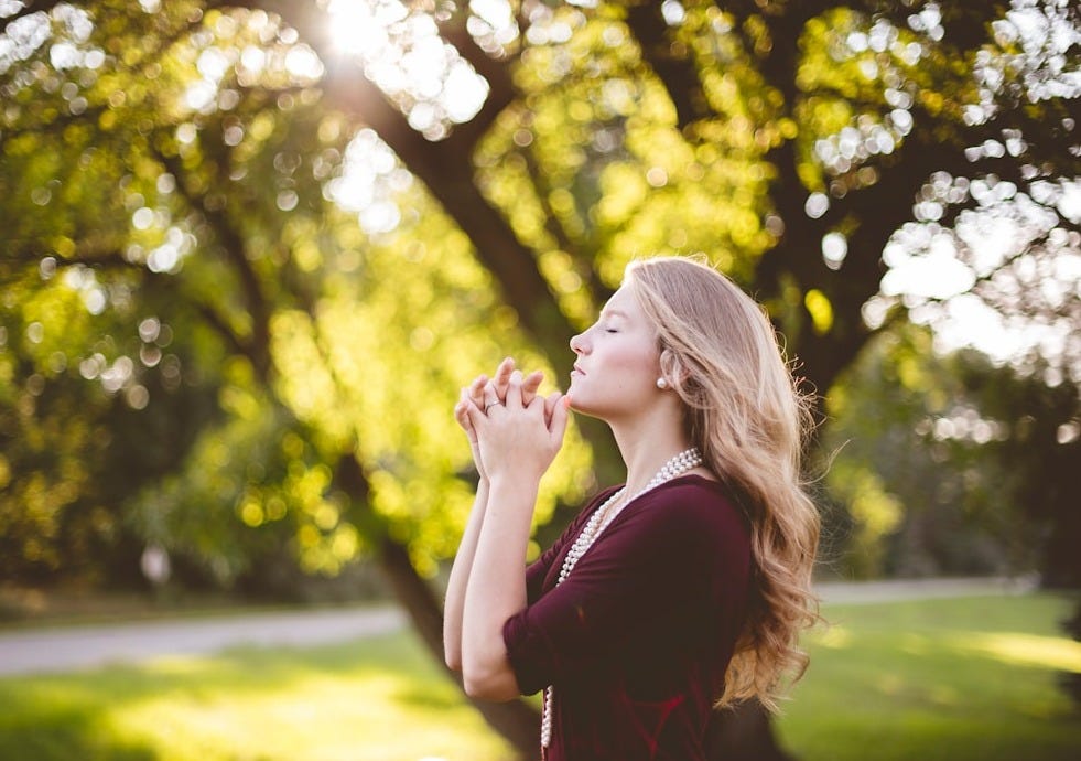 The One Thing: woman praying under tree in summer daylight