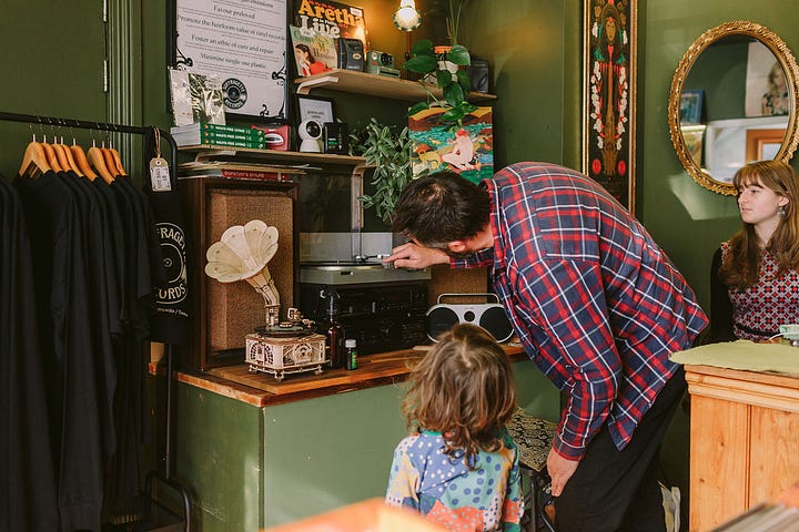 1 & 4 Oberon and Xanthe chat about preloved records with the local community. 2. Oberon shows an eco-vinyl record made from waste plastics in a carbon neutral process. 3. Oberon demonstrates his method of record repair, with a microscope. 5. Oberon shows a young visitor how to care for record players and how they work.