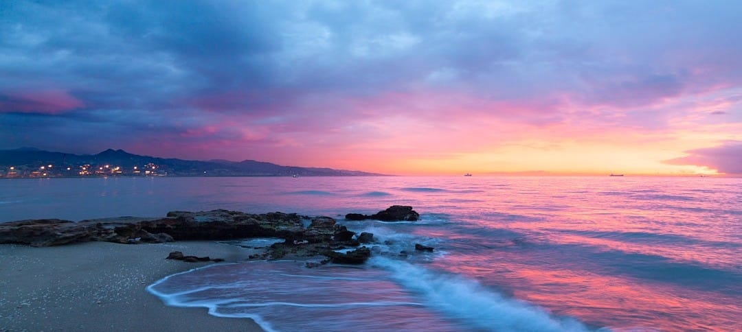 waves of body of water splashing on sand