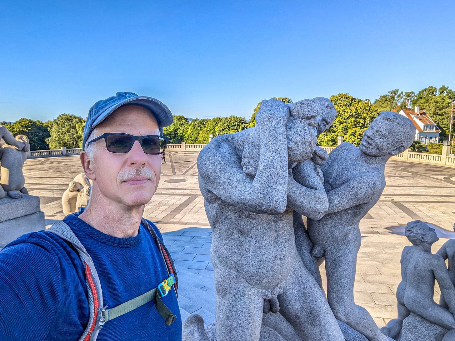 Michael standing next to a granitce sculpture depicting two boys assaulting a man. 