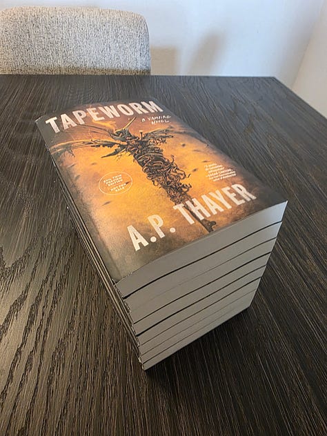 Paperback ARC stack of books, titled Tapeworm, by A.P. Thayer, a horror novel