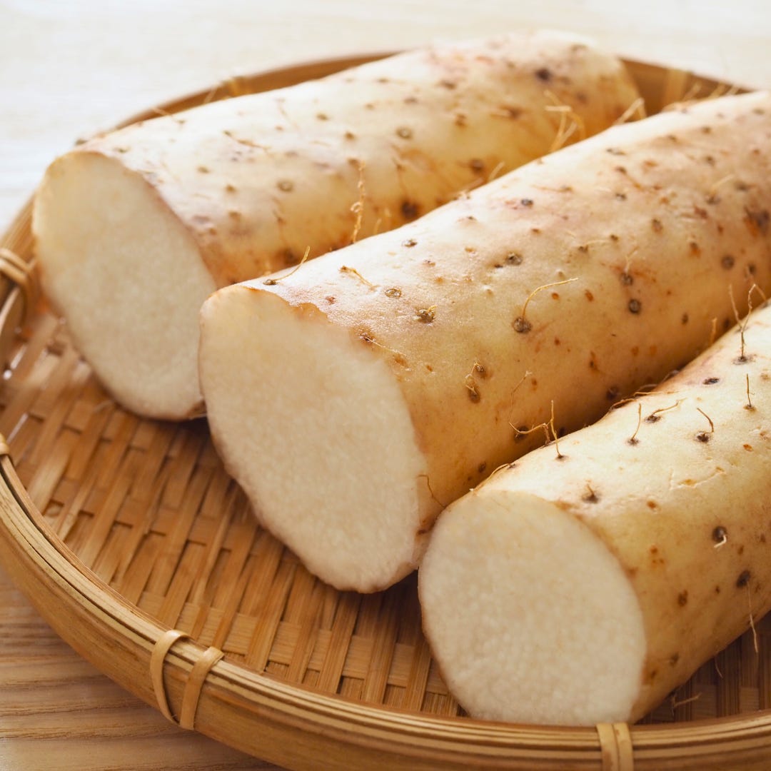 Several Japanese mountain yams (nagaimo) resting on a bamboo strainer.