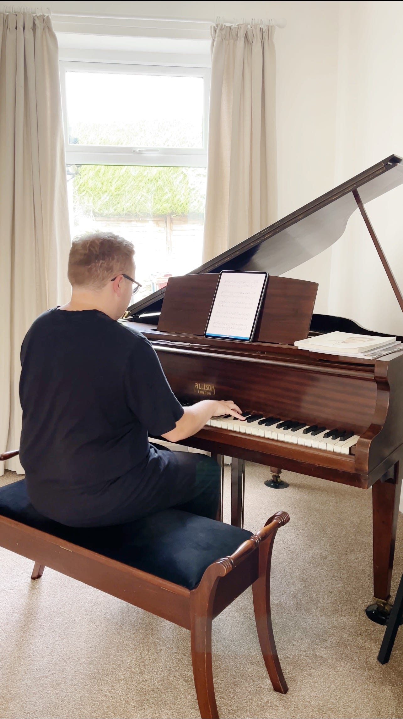 Jack Watkins sits at his grand piano whom he calls “Allison” based on the maker brand. See a close-up view of the piano keys.