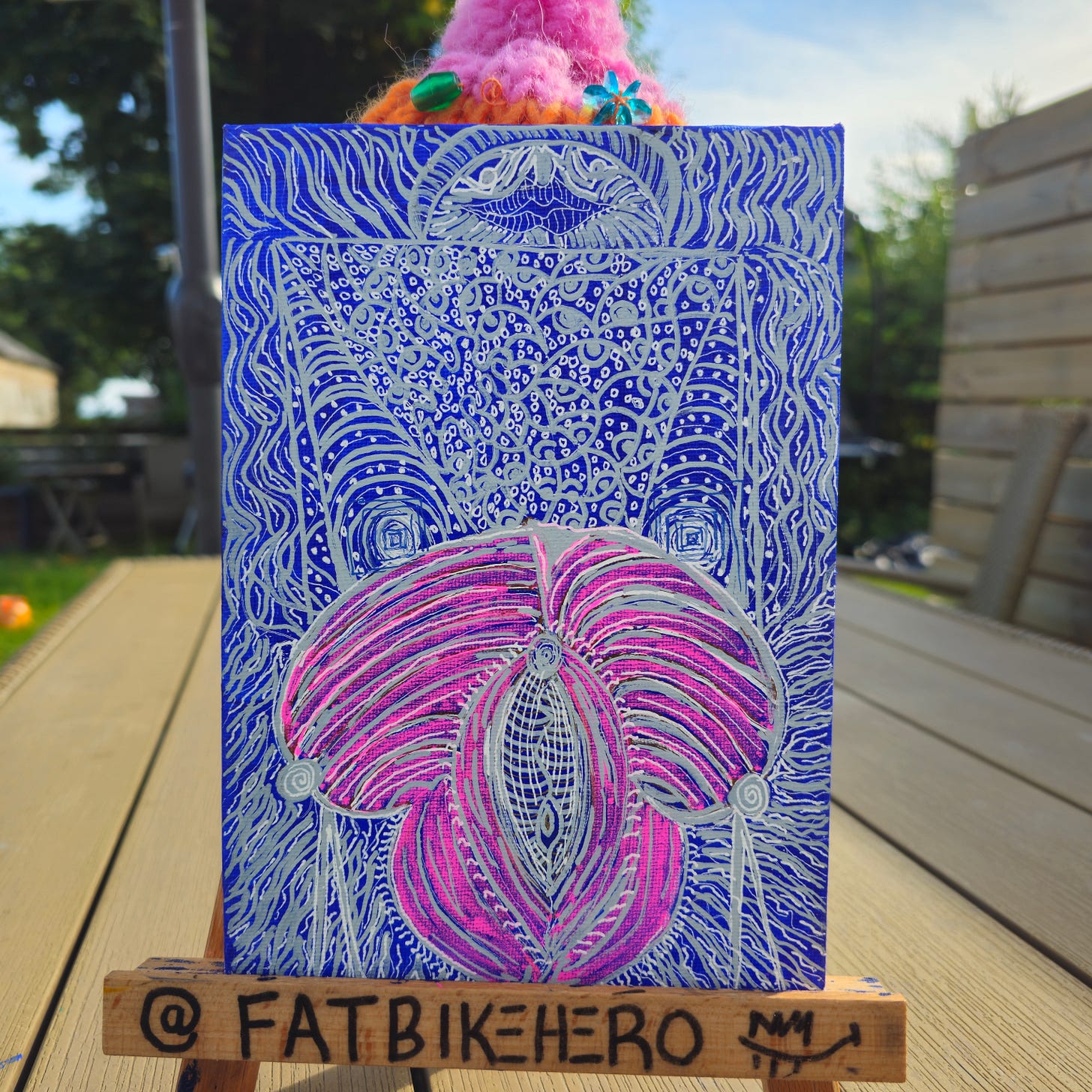 Alt Text: A vertical acrylic painting titled "The Vulva" by FatbikeHero. A vibrant, abstract pink and magenta organic form sits centrally against a deep cobalt blue background covered in intricate, labyrinthine silver linework and geometric doodle patterns.