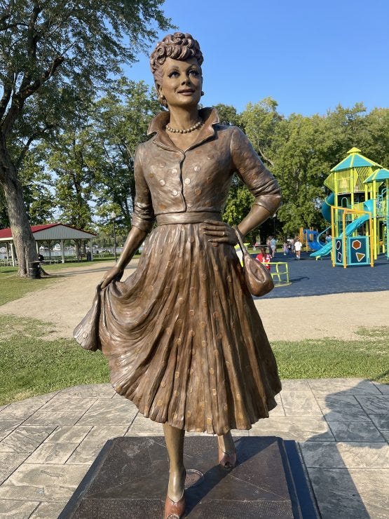 A bronze statue captures the iconic spirit of Lucille Ball in her hometown of Jamestown, NY, wearing a classic 1950s dress with her characteristic confident pose and warm smile. ©Tamara MC, Ph.D.