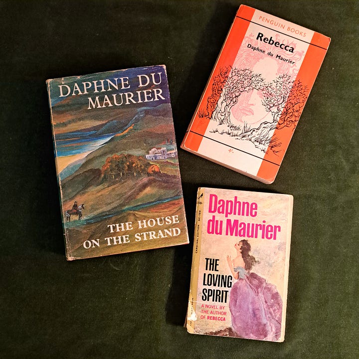 three old Daphne du Maurier books on green velvet and a paperback copy of The Witch of Blackbird Pond on dark, gauzy fabric