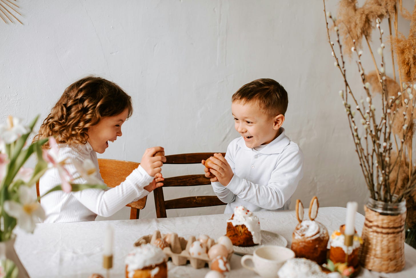 A girl and a boy sitting at a table facing each other and laughing