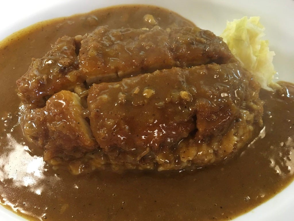 sliced tonkatsu covered in and also surrounded by brown Japanese curry sliced tonkatsu covered in and also surrounded by brown Japanese curry