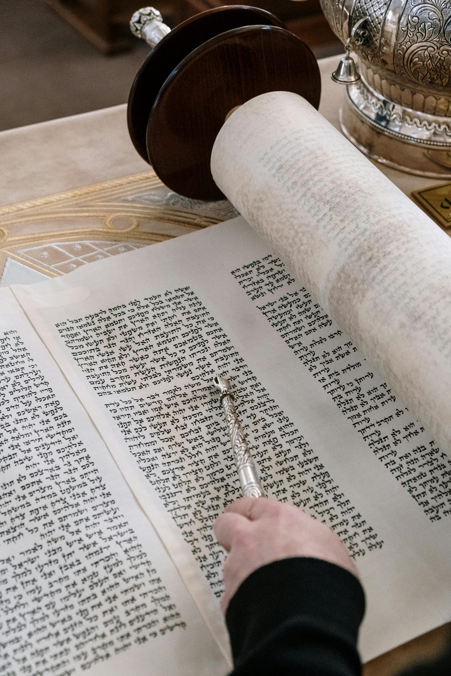 Open Torah with silver pointer at the text, with silver torah crown at upper right