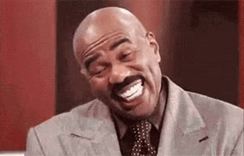a bald man with a mustache is laughing with his mouth open while wearing a suit and tie . a bald man with a mustache is laughing with his mouth open while wearing a suit and tie .