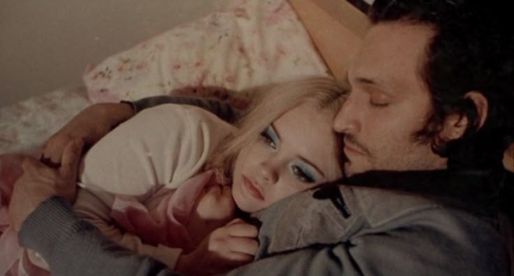 This may contain: a man and woman cuddle together on a bed