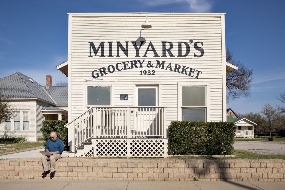 The author of this newsletter seated outside a vintage building labeled "Minyard's Grocery & Market: 1932" The author of this newsletter seated outside a vintage building labeled "Minyard's Grocery & Market: 1932"