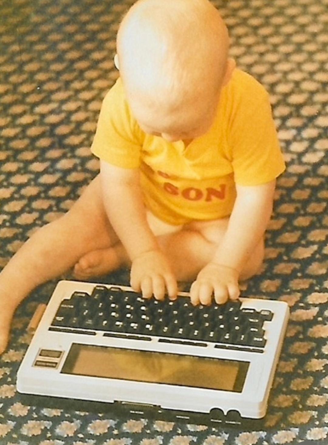 A baby sitting on the floor using a keyboard

Description automatically generated