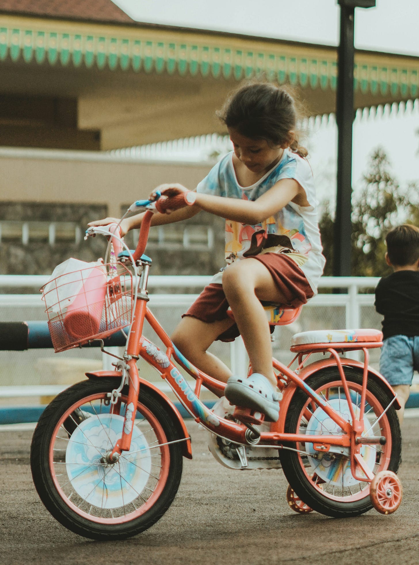 A girl rides her bike with training wheels.