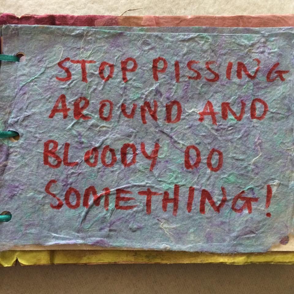 'stop pissing around and bloody do something' written by hand in red on handmade paper