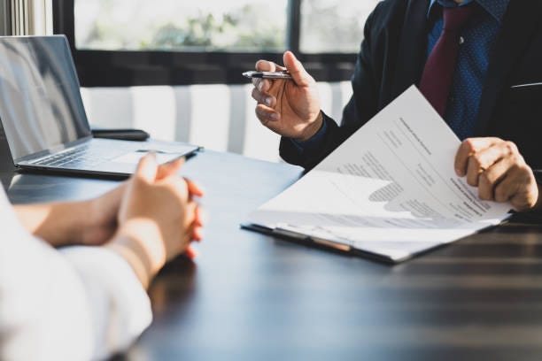 Businessman in suit in his office showing an insurance policy and pointing with a pen where the policyholder must to sign. Insurance agent presentation and consulting insurance detail to customer. Businessman in suit in his office showing an insurance policy and pointing with a pen where the policyholder must to sign. Insurance agent presentation and consulting insurance detail to customer. estate planning stock pictures, royalty-free photos & images