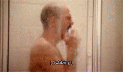 a man is taking a shower and brushing his teeth in the bathroom .