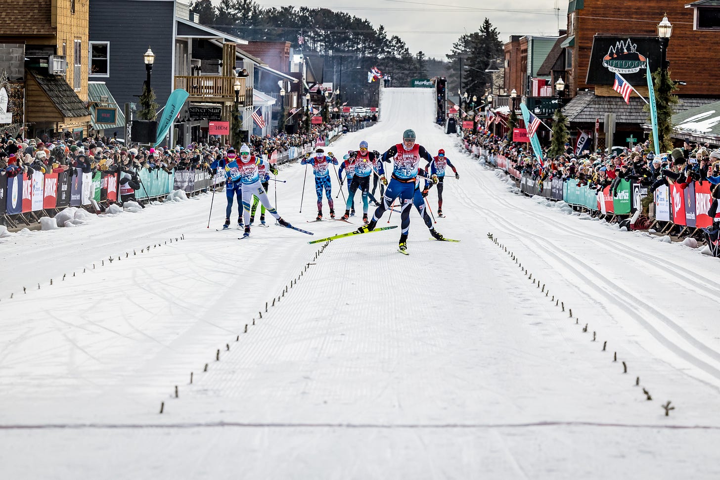 Cross-country skiers race toward the finish on snow-covered Main Street in Hayward, Wisconsin, during the American Birkie, with spectators lining both sides of the course. Cross-country skiers race toward the finish on snow-covered Main Street in Hayward, Wisconsin, during the American Birkie, with spectators lining both sides of the course.