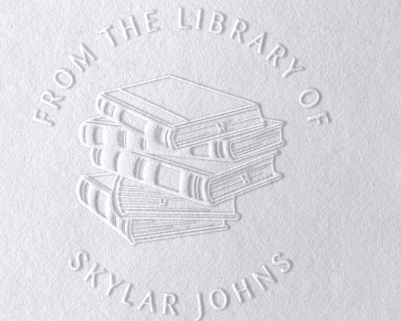 May include: A white embossed stamp with the text 'From the Library of Skylar Johns' in a circle around an image of a stack of four books.