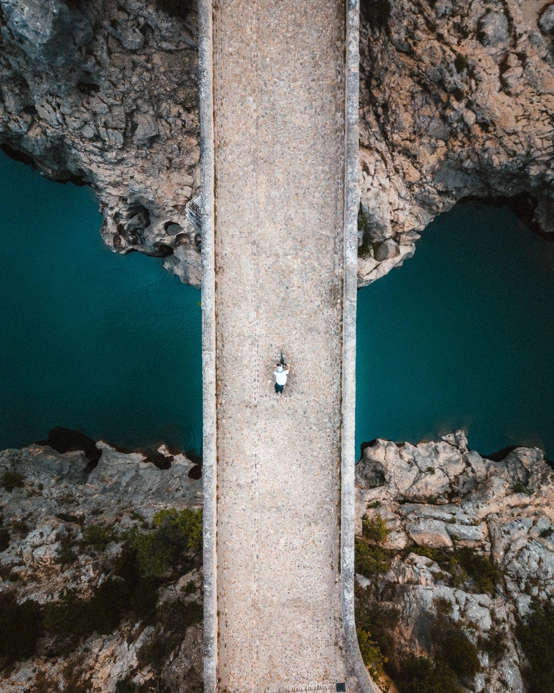 Vue de haut d'un cycliste traversant un pont en pierre