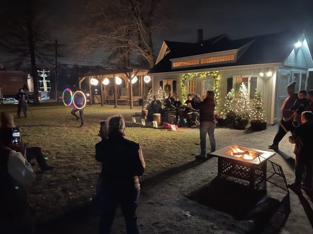 A community gathers around a fire pit outdoors at the Corner Spot in Ashland, MA.