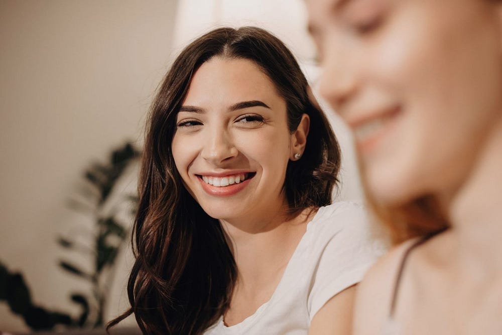 Two young women — one in focus, one blured.
