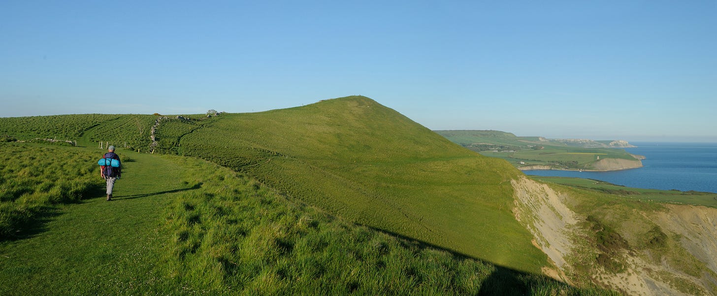 hiker on green path high above the sea in Dorset