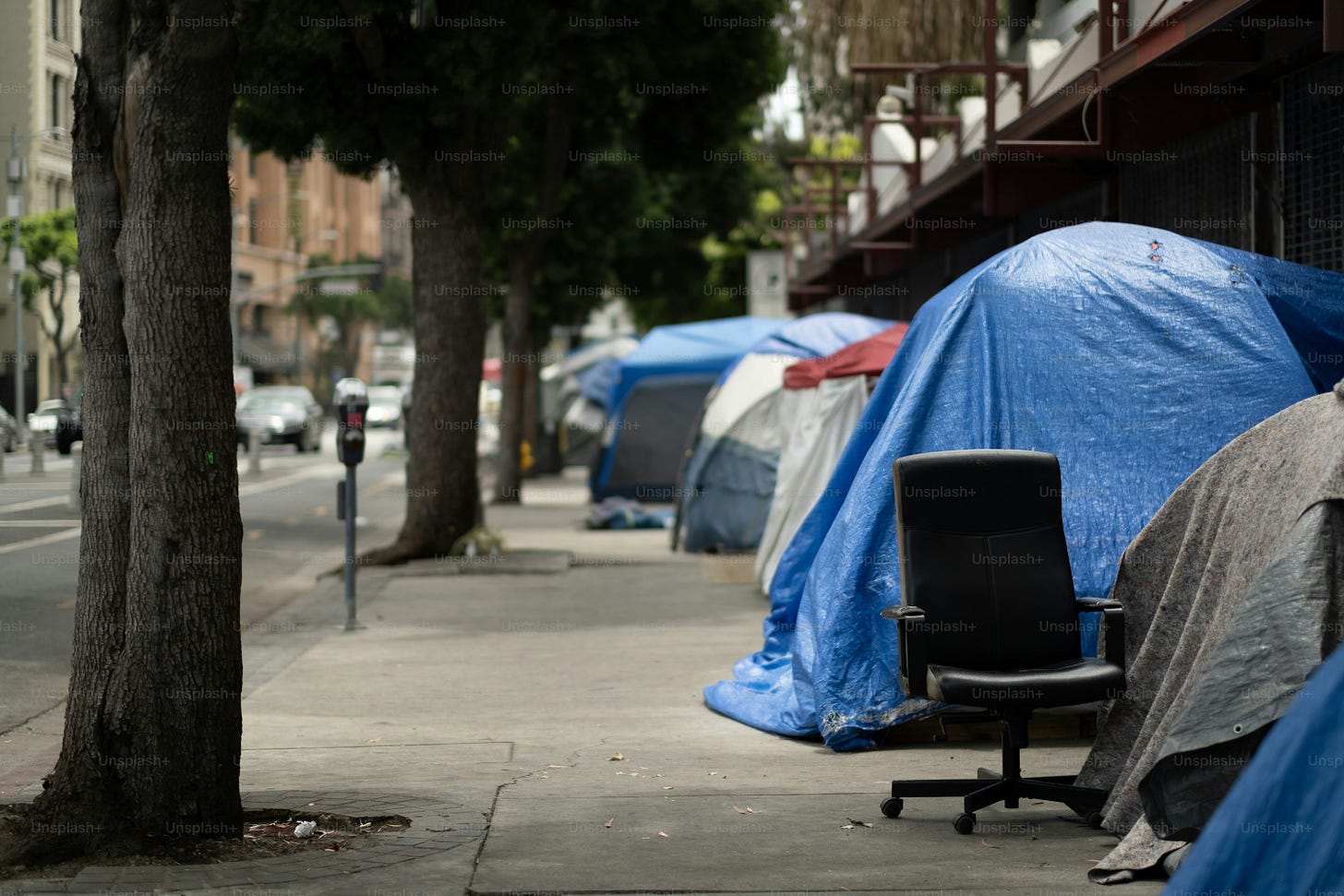 a chair sitting on a sidewalk next to a bunch of tents a chair sitting on a sidewalk next to a bunch of tents