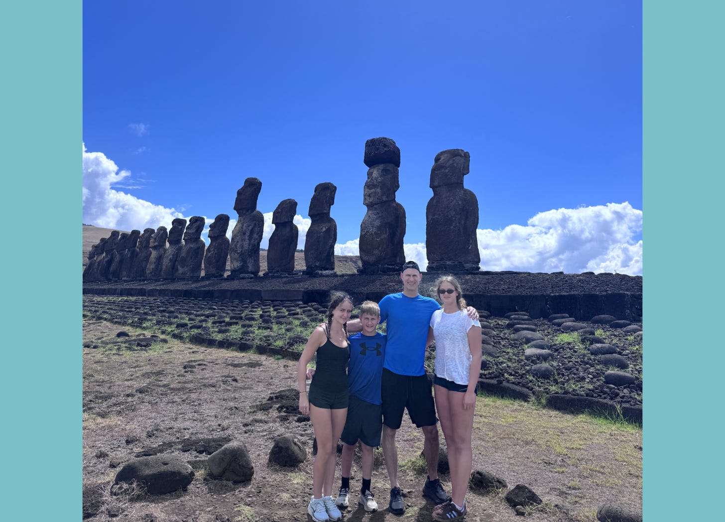 Photo of a dad with three kids posed in front of statues on Easter Island